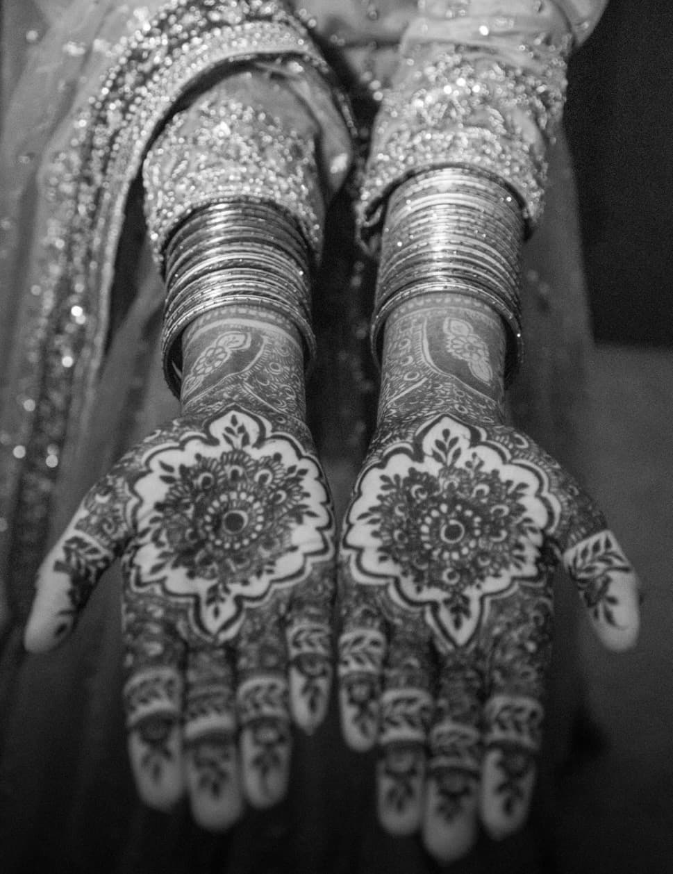 Detailed henna design on open palms with layered bangles
