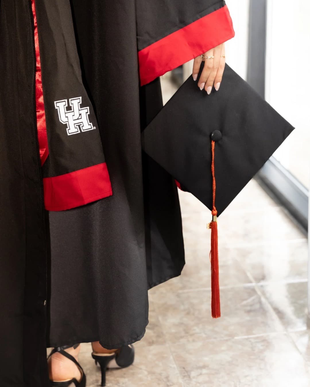 Detail of a graduation gown sleeve and cap with red tassel