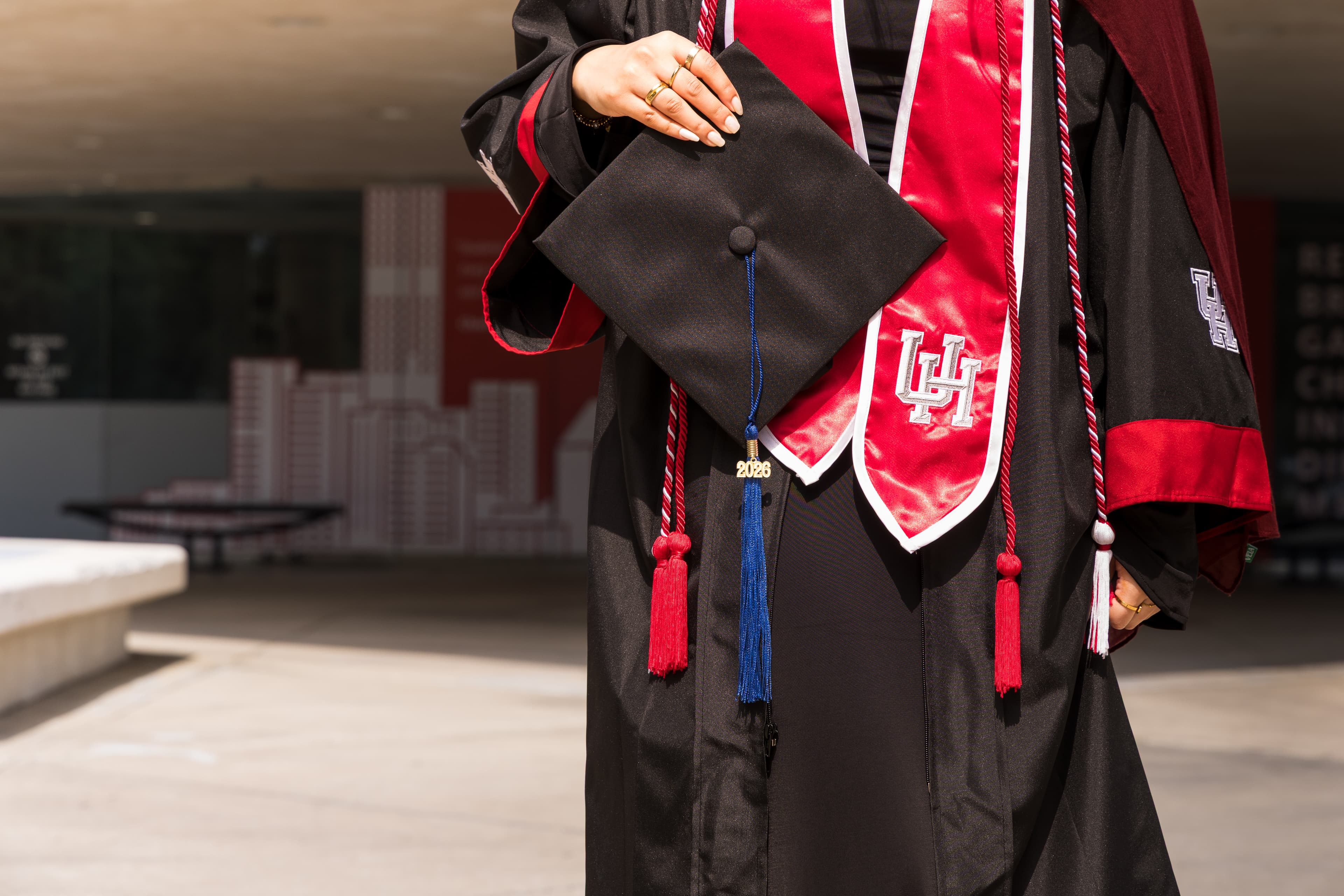 Graduate holding her cap, showing a University of Houston stole detail