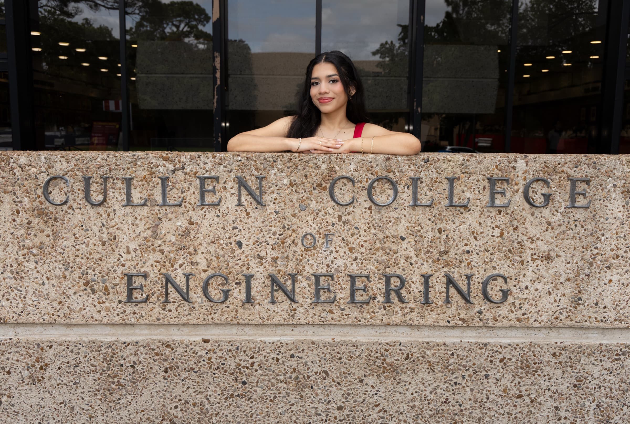 Graduate leaning on the Cullen College of Engineering sign at University of Houston