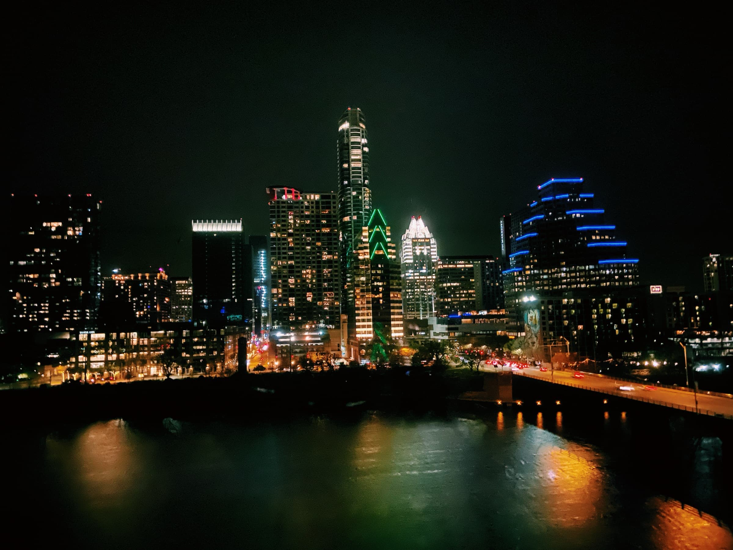 City skyline lit up at night above a river and bridge