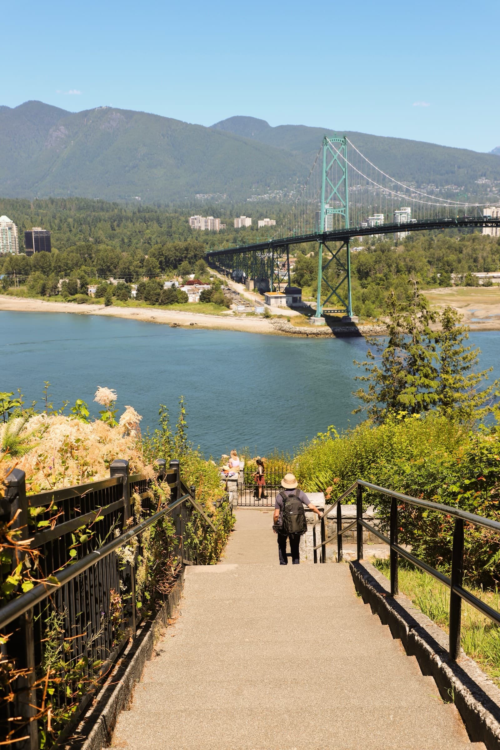 Hiker descending a staircase toward a suspension bridge over the water