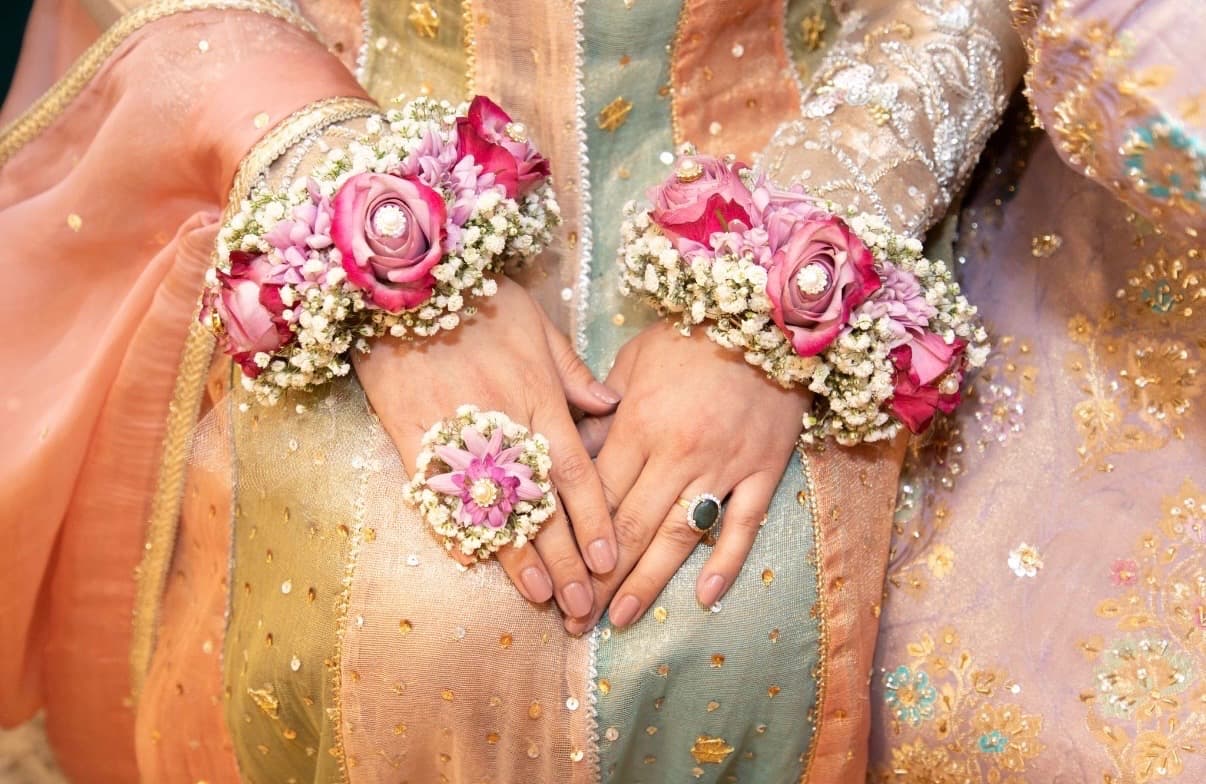 Hands adorned with floral gajra bracelets and a pastel embroidered outfit