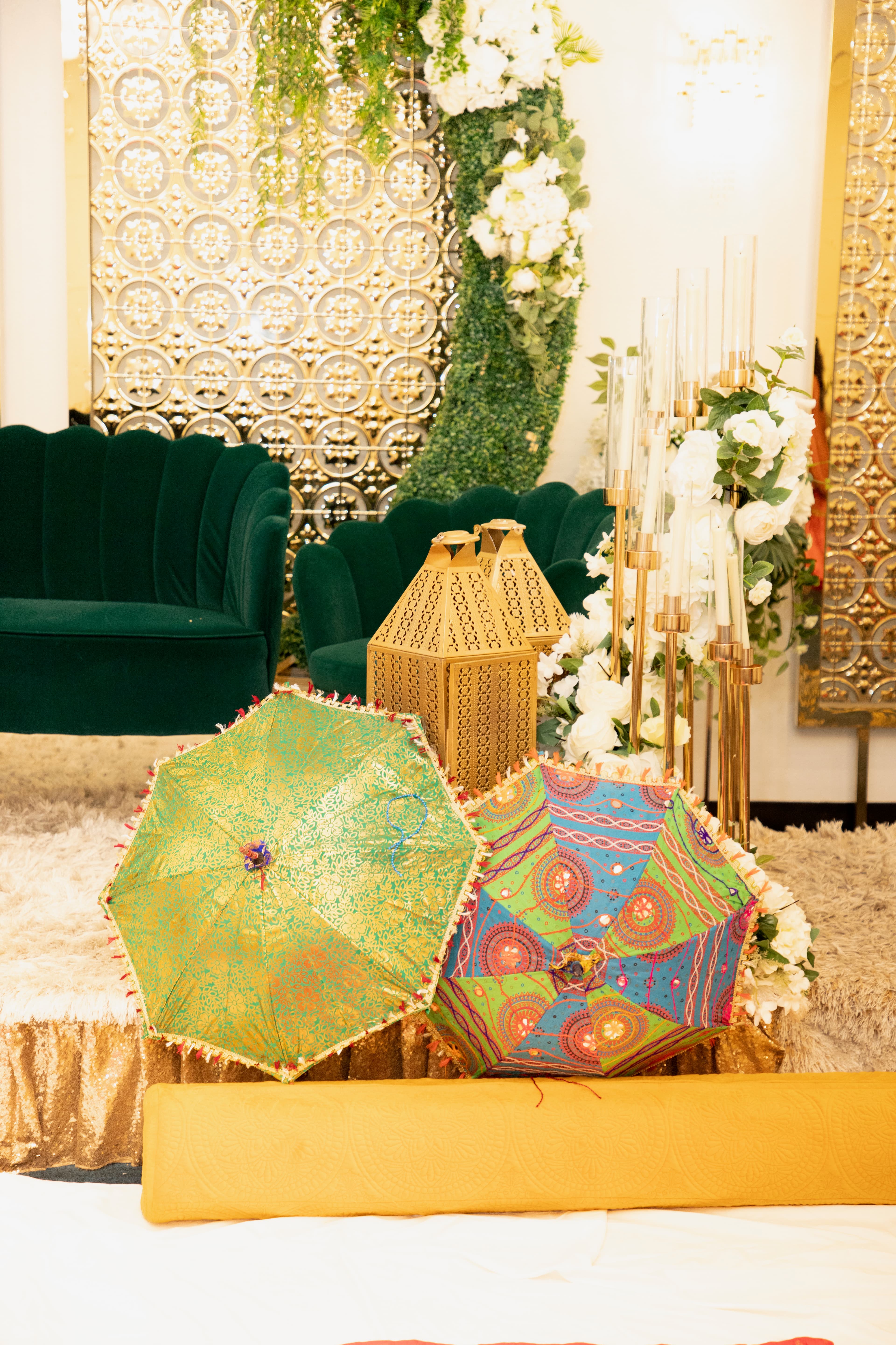 Decorative painted umbrellas on a mehndi stage with green sofas