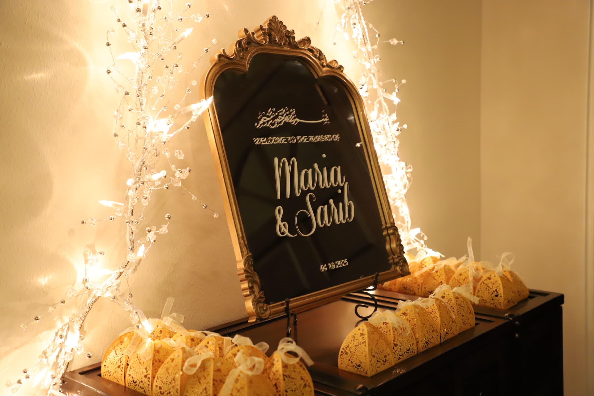 Illuminated mirror welcome sign for a wedding ruksati, framed by fairy lights and favor boxes