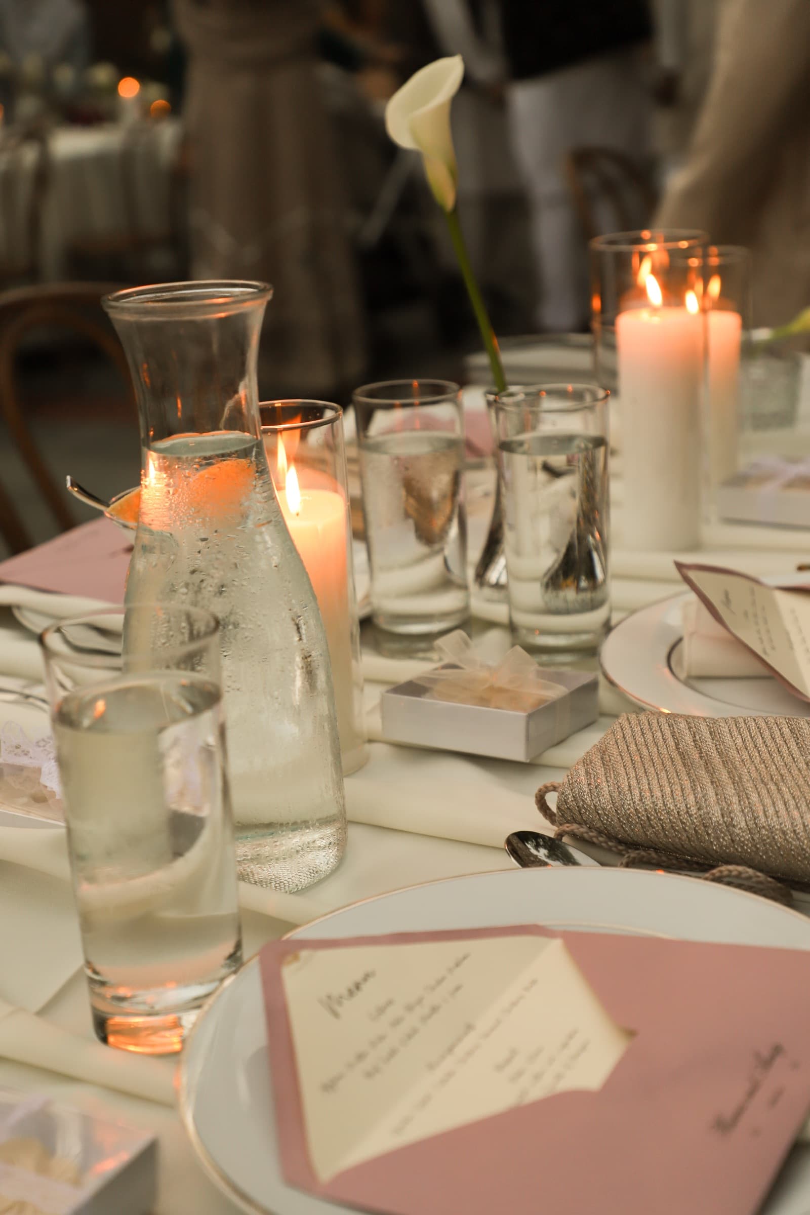 Reception table setting with candlelight, water carafes, and menu cards